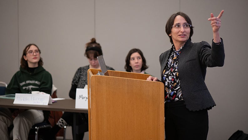 Andrea Weiss speaking at the podium at the NY intensive